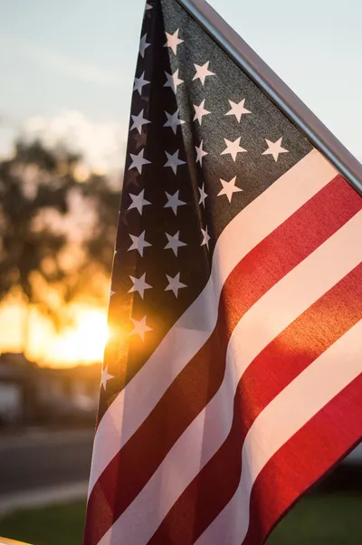 A close up of the american flag in front of a sunset