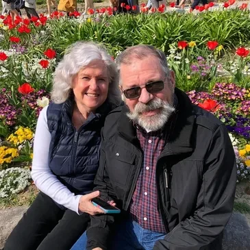 A man and woman sitting in front of flowers.